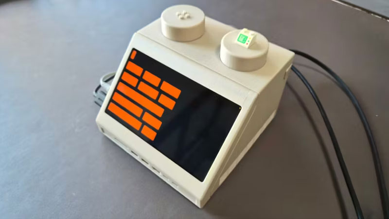 המק מיני נסתם בתוך קוביית LEGO מורחבת מעוצבת כטרמינל משנות ה-70